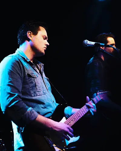 Dirk met gitaar in blauw podiumlicht
